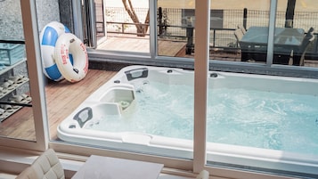 Un jacuzzi con terraza de madera y vista a un espacio exterior cercado.