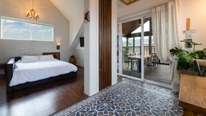 A bedroom with a bed, a chandelier, a brick wall, a wooden ceiling, and a view of the outdoors. - Gyeongju Suite Cream Hill Pension (Gyeongju)