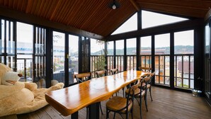 A spacious room with a long wooden table and chairs, large windows offering a view of the surrounding area, and a ceiling with wooden beams. - Gyeongju Suite Cream Hill Pension (Gyeongju)
