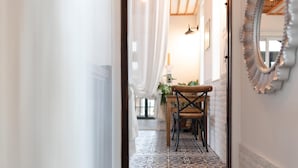 A hallway with a patterned floor, a wooden chair, a mirror, and a door leading to a room with a lamp and a plant. - Gyeongju Suite Cream Hill Pension (Gyeongju)