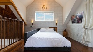 A bedroom with a bed, a window, a chandelier, a picture on the wall, and a staircase. - Gyeongju Suite Cream Hill Pension (Gyeongju)