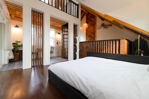 A bedroom with a large bed, wooden ceiling beams, and a view of a balcony.
