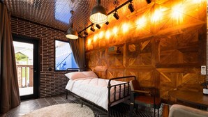 A bedroom with a bed, a wooden wall, a window, and a door. - Gyeongju Suite Cream Hill Pension (Gyeongju)