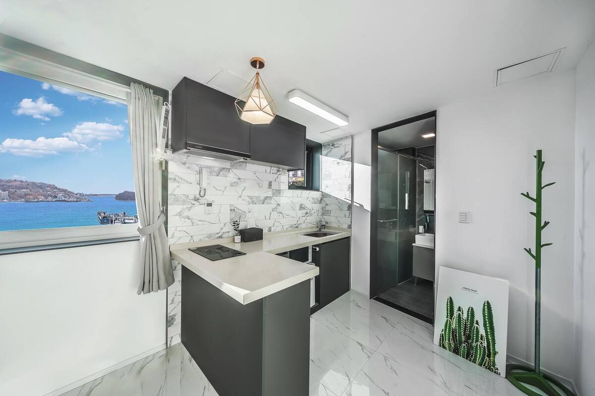 A modern kitchen with a view of the sea, a marble backsplash, and a minimalist design.