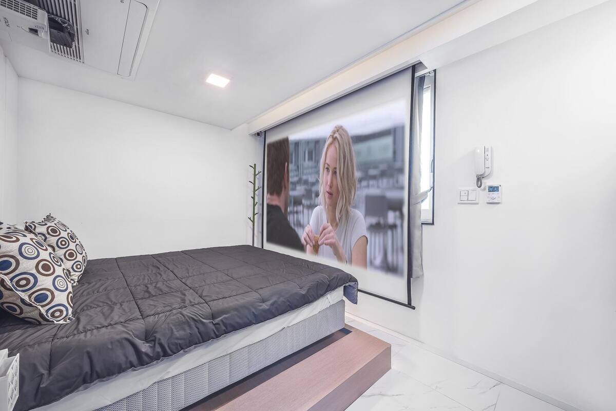 A modern bedroom with a bed, a large window, and a wall-mounted air conditioning unit.