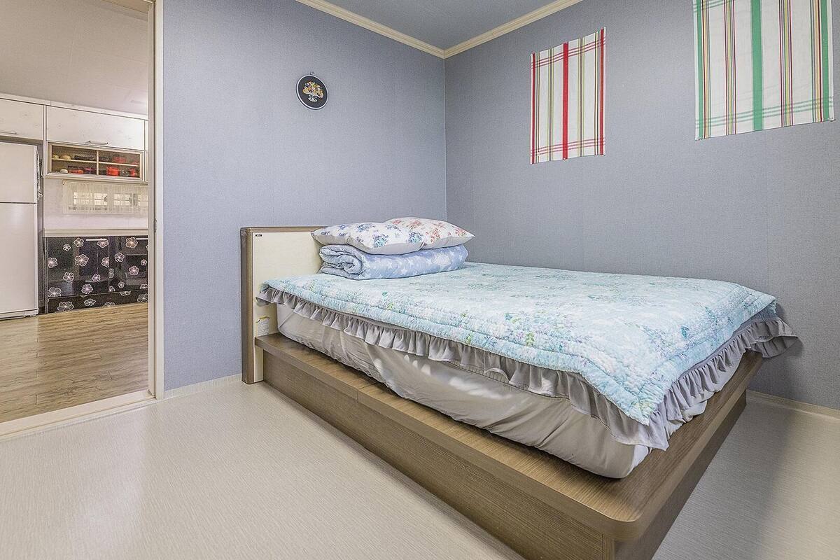 A bedroom with a bed, a wardrobe, and a small wall decoration.