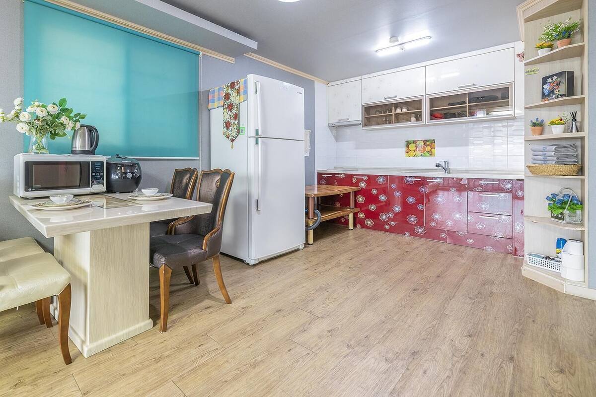 A compact kitchen with a microwave, toaster, and refrigerator. There is a dining area with a table and chairs.