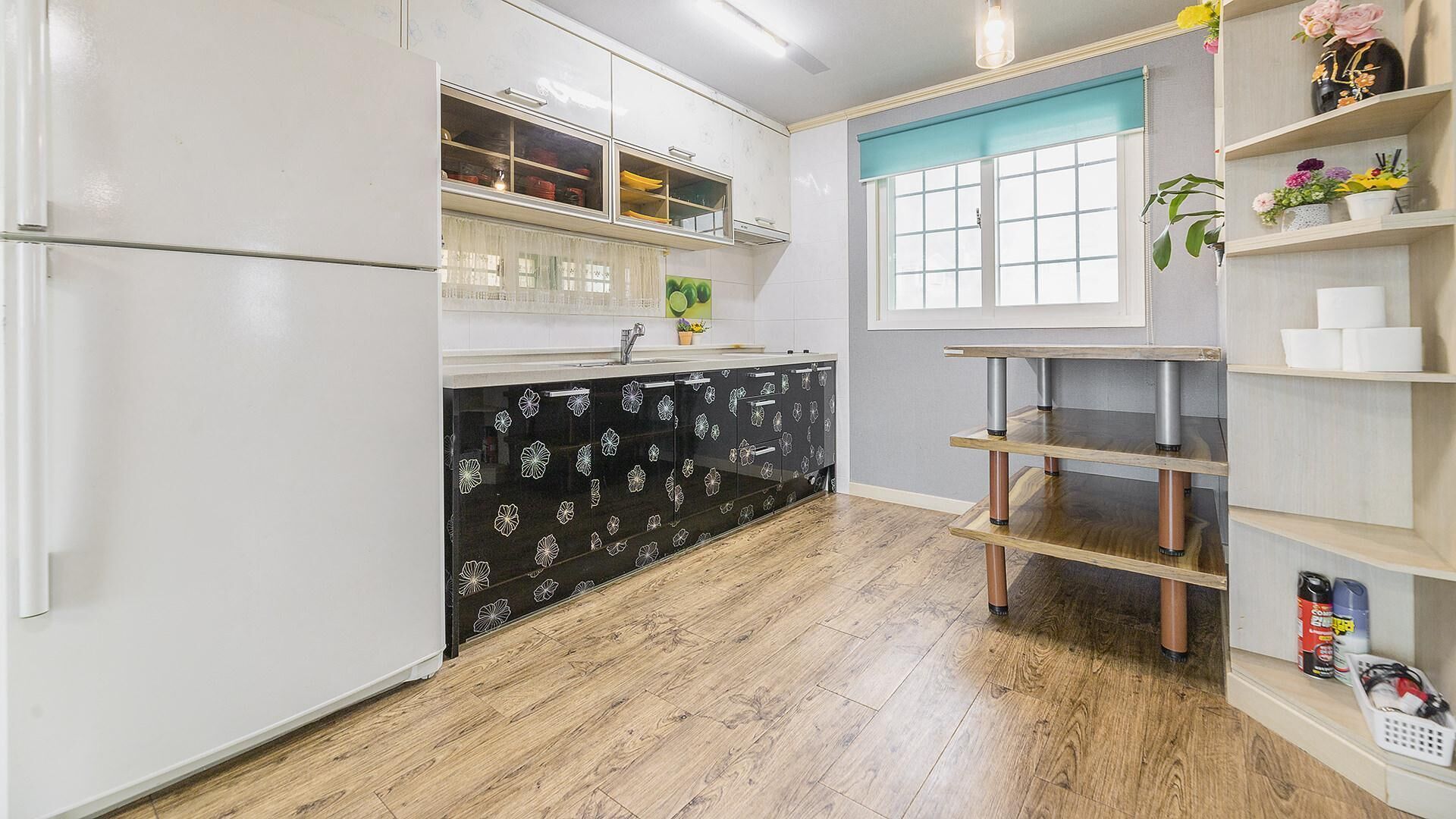 A kitchen with white cabinets, a black patterned countertop, and wooden flooring.