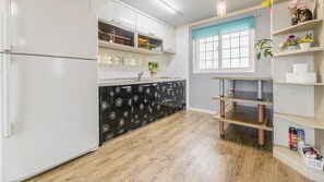 Cocina con armarios blancos, encimera con estampado oscuro y suelo de madera.
