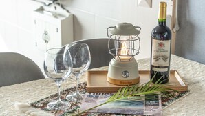 A table with two wine glasses, a bottle of wine, a lamp, and a newspaper. - Ganghwa Badatgashimteo Pension (Incheon)