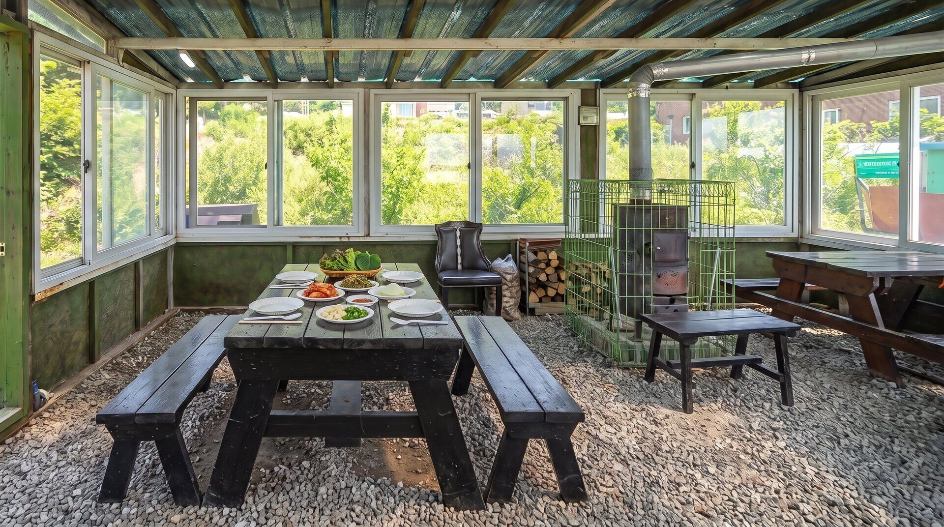 A covered outdoor dining area with a table set for a meal, surrounded by benches and a grill.