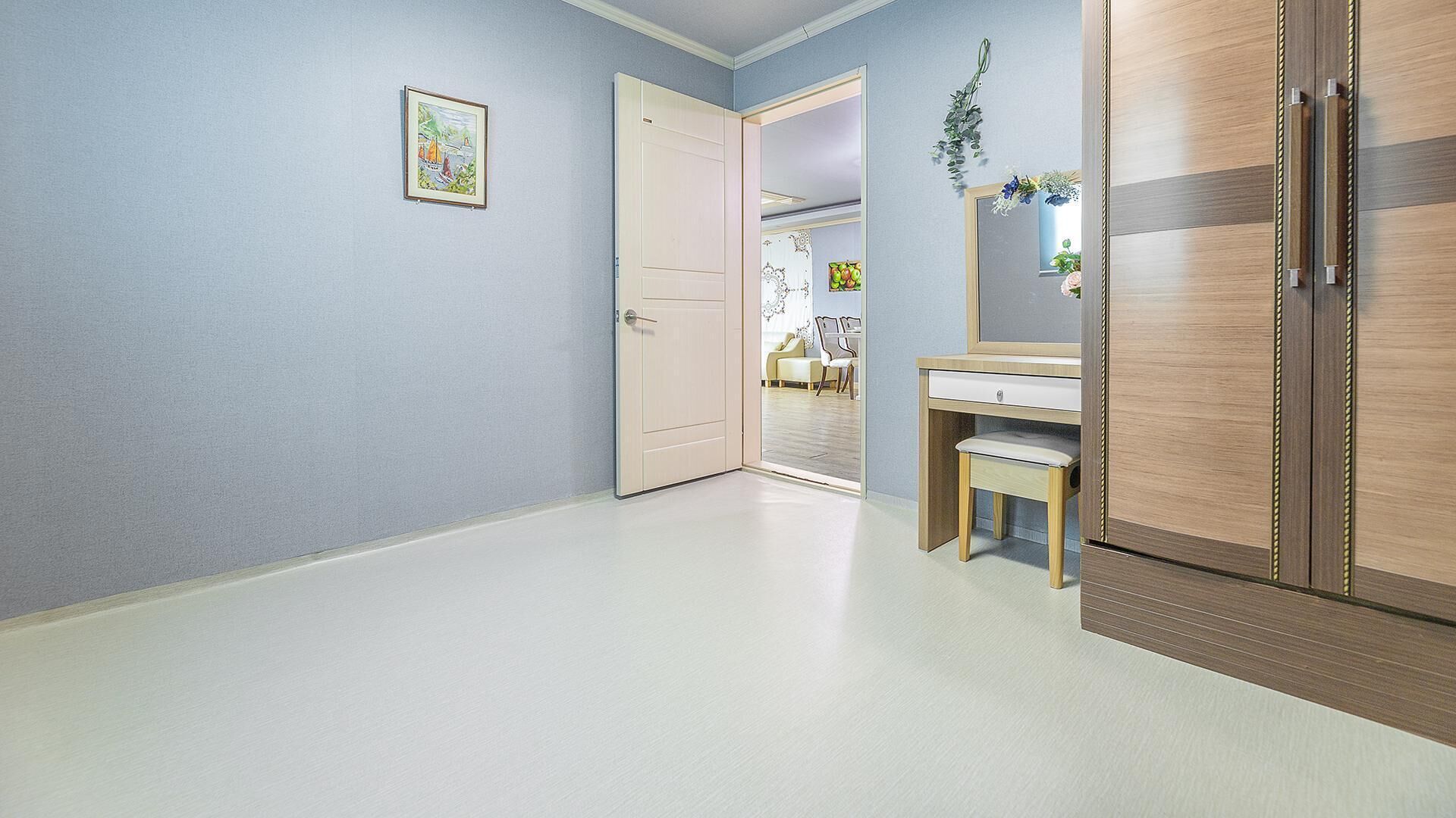 Ein Flur mit einer Tür zu einem Zimmer, einem Holzschrank und einem kleinen Schreibtisch mit Stuhl.