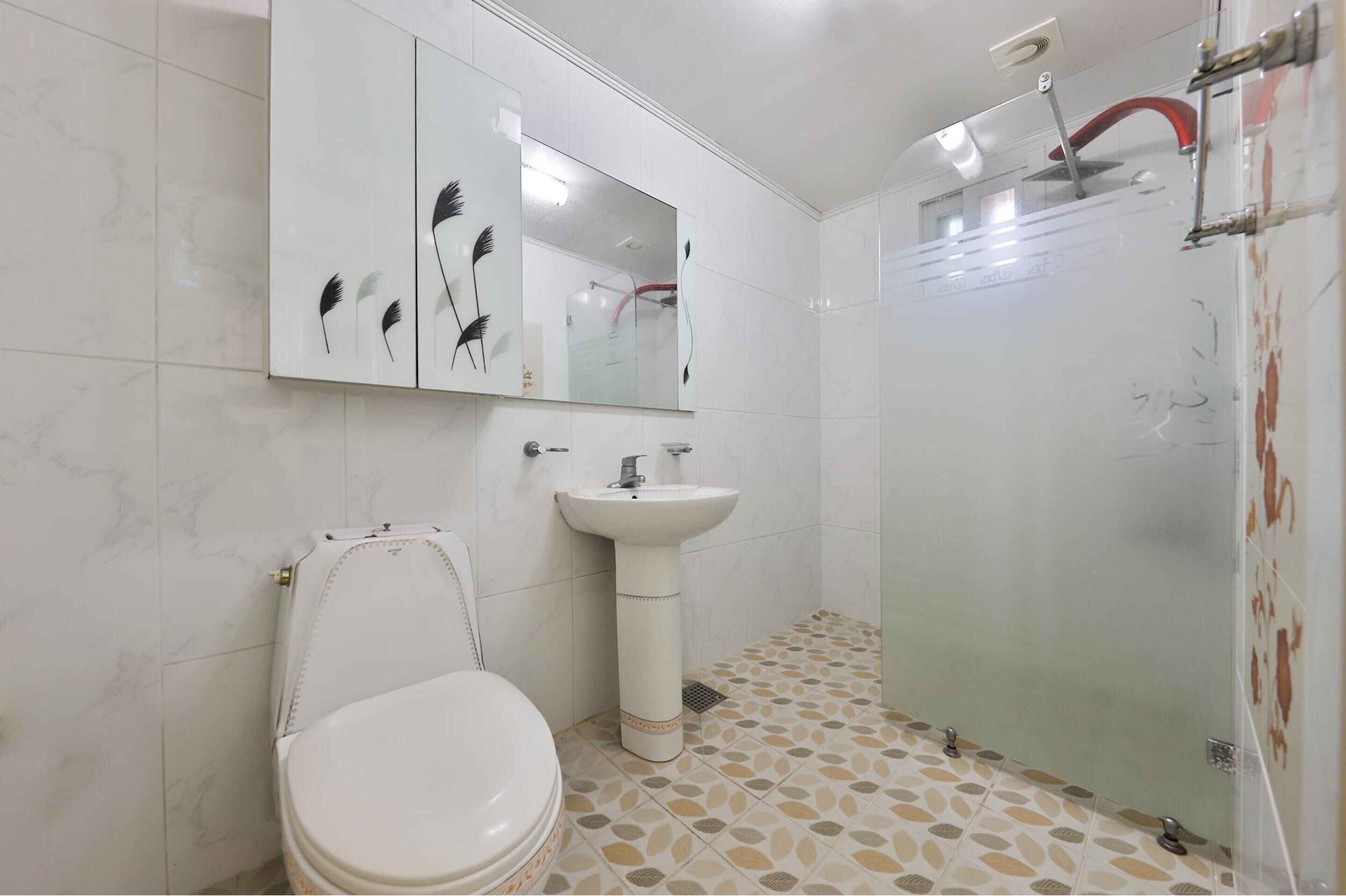 A bathroom with a toilet, sink, and glass shower enclosure.