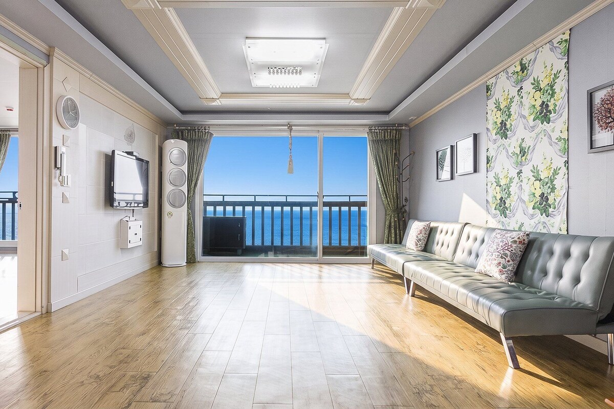 A spacious living room with a balcony, a television, and a sofa.