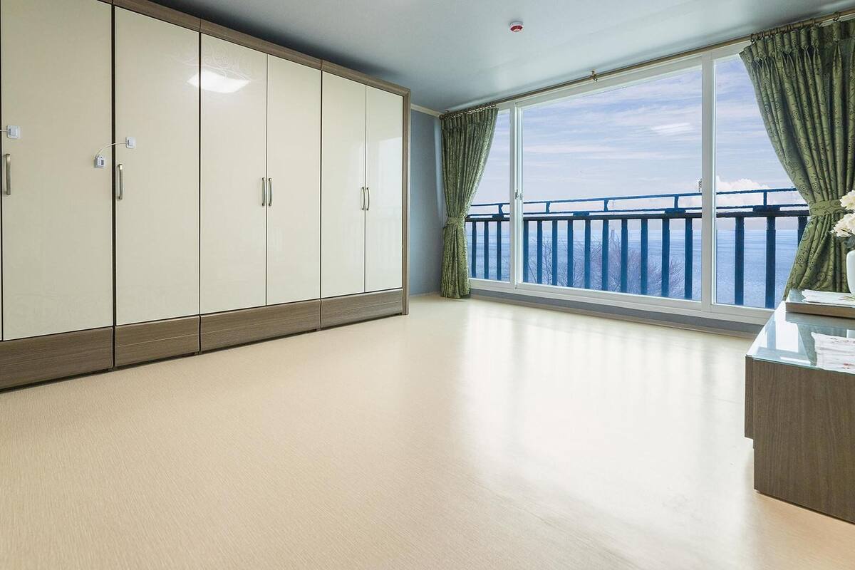 A spacious room with a large wardrobe, a balcony with a view, and a small table with a vase.