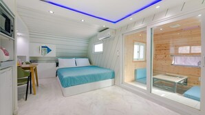 A modern bedroom with a bed, a desk, and a sliding glass door leading to a wooden deck. - Gapyeong Poongkyungmaru Pension (Gapyeong)