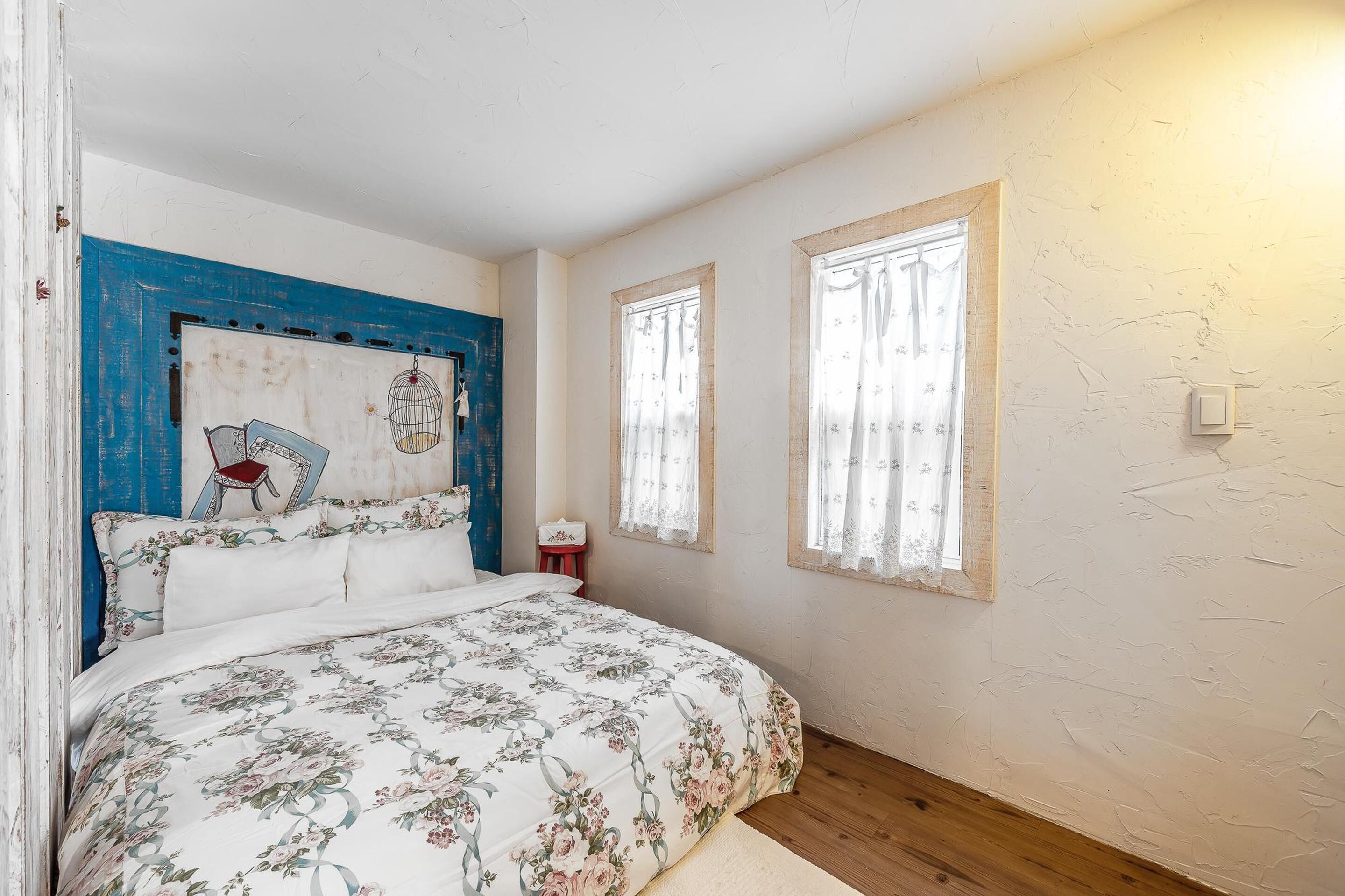 A bedroom with a bed, a nightstand, a chair, and a window with curtains.