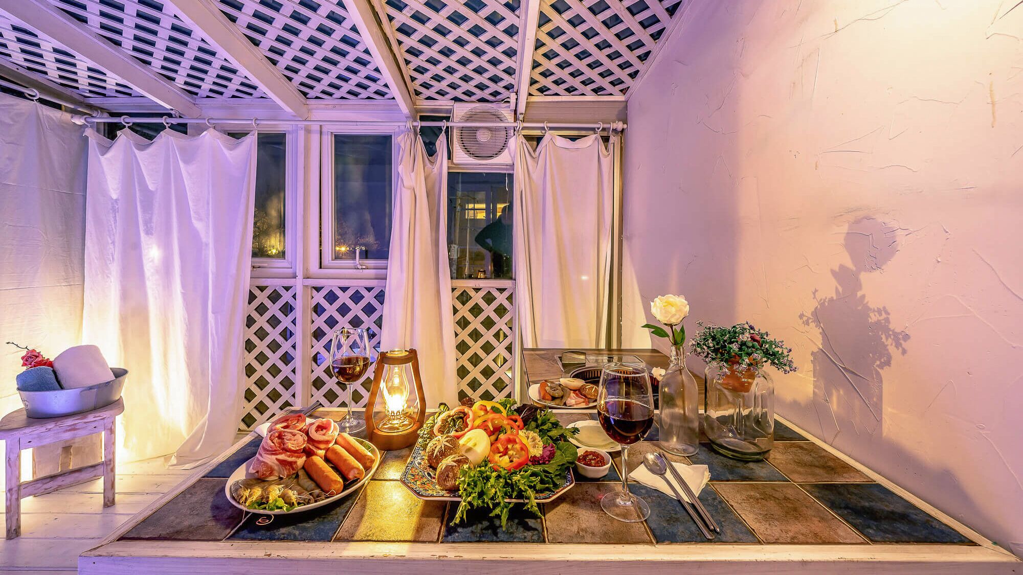 Un comedor con una mesa dispuesta para una comida, incluyendo platos de comida, una copa de vino y una vela.