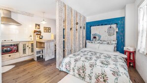A bedroom with a bed, a wooden desk, a red chair, a blue wall, and a white ceiling. - Ganghwa Vintage Box Pension (Incheon)