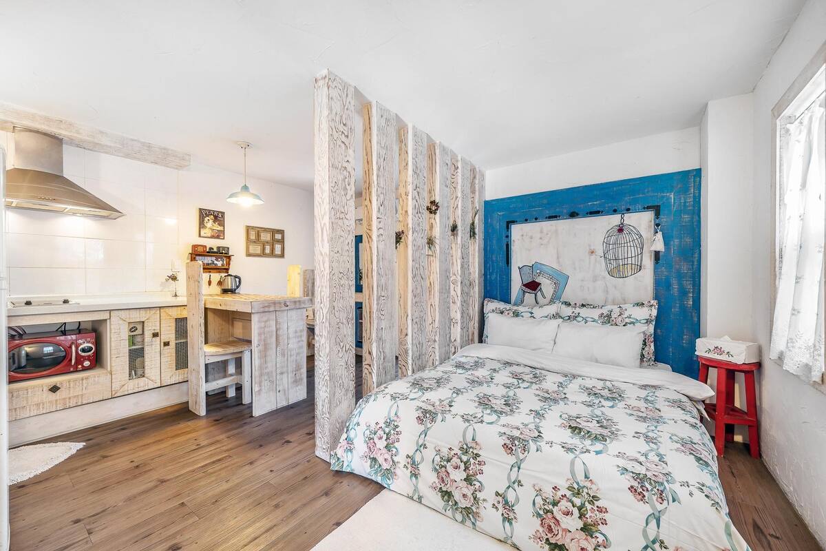 Une chambre à coucher avec un lit, un bureau en bois, une chaise rouge, un mur bleu et un plafond blanc.