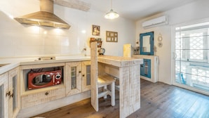 A compact kitchen with a built-in microwave, wooden cabinetry, and a window with a view. - Ganghwa Vintage Box Pension (Incheon)
