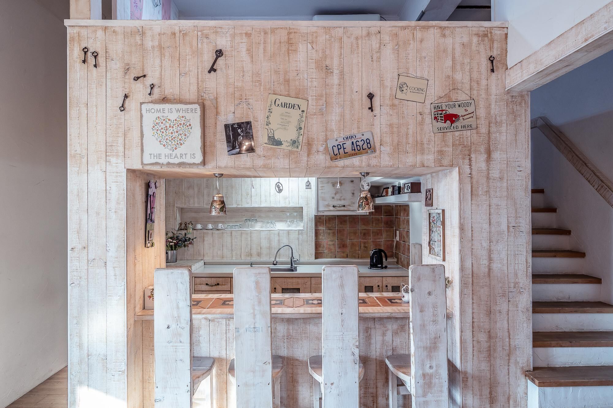 A kitchen with wooden cabinets, a hanging light fixture, and a sign that says 'HOME IS WHERE THE HEART IS'.