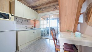 Une cuisine avec des meubles blancs, un four à micro-ondes et une fenêtre donnant sur un balcon.