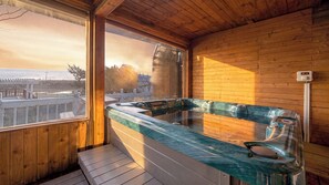 A wooden cabin with a glass-enclosed hot tub and a view of the beach. - Ganghwa Izba Pension (Incheon)