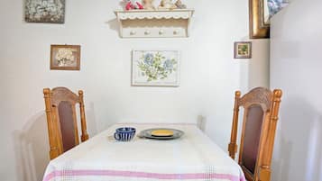 A dining table with a white tablecloth and a blue cup, flanked by wooden chairs with carved details.