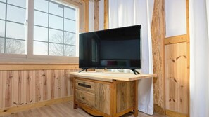 Un intérieur en bois avec un téléviseur posé sur un meuble, une fenêtre et une porte.