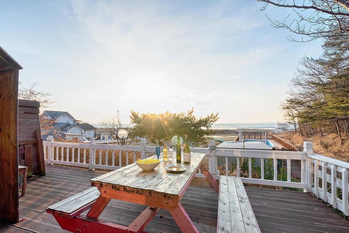 A wooden deck with a picnic table, bottles, and a bowl of lemons.