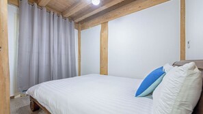 A bedroom with a wooden ceiling, a bed with white bedding and two pillows, and a window with curtains. - Ganghwa Izba Pension (Incheon)