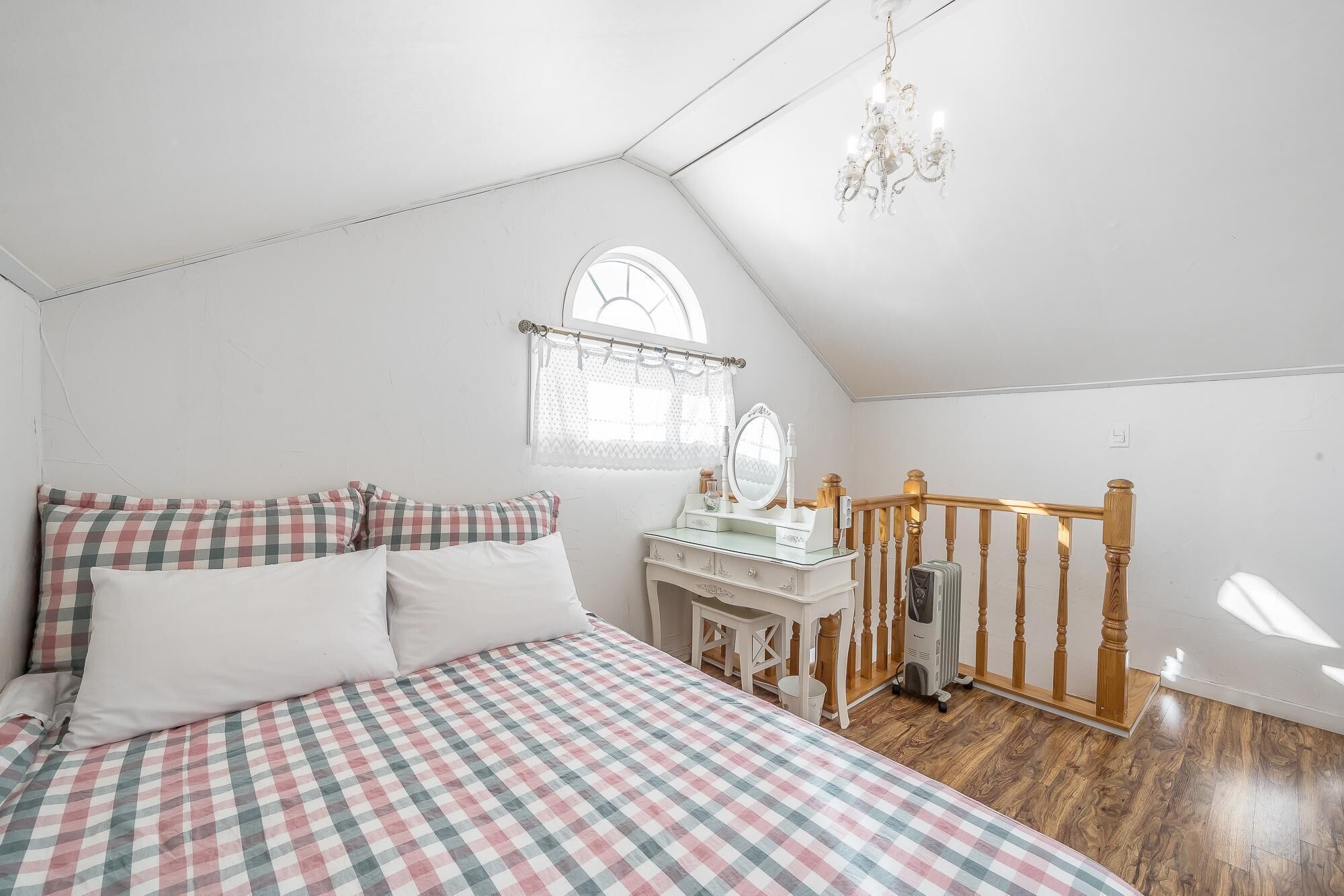 Une chambre à coucher avec une couvre-lit à carreaux, une coiffeuse avec un miroir et un lustre.