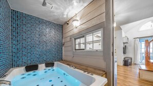 A modern bathroom with a large bathtub, blue mosaic tiles, and a wooden floor. - Ganghwa Edenjungwon Pension (Incheon)