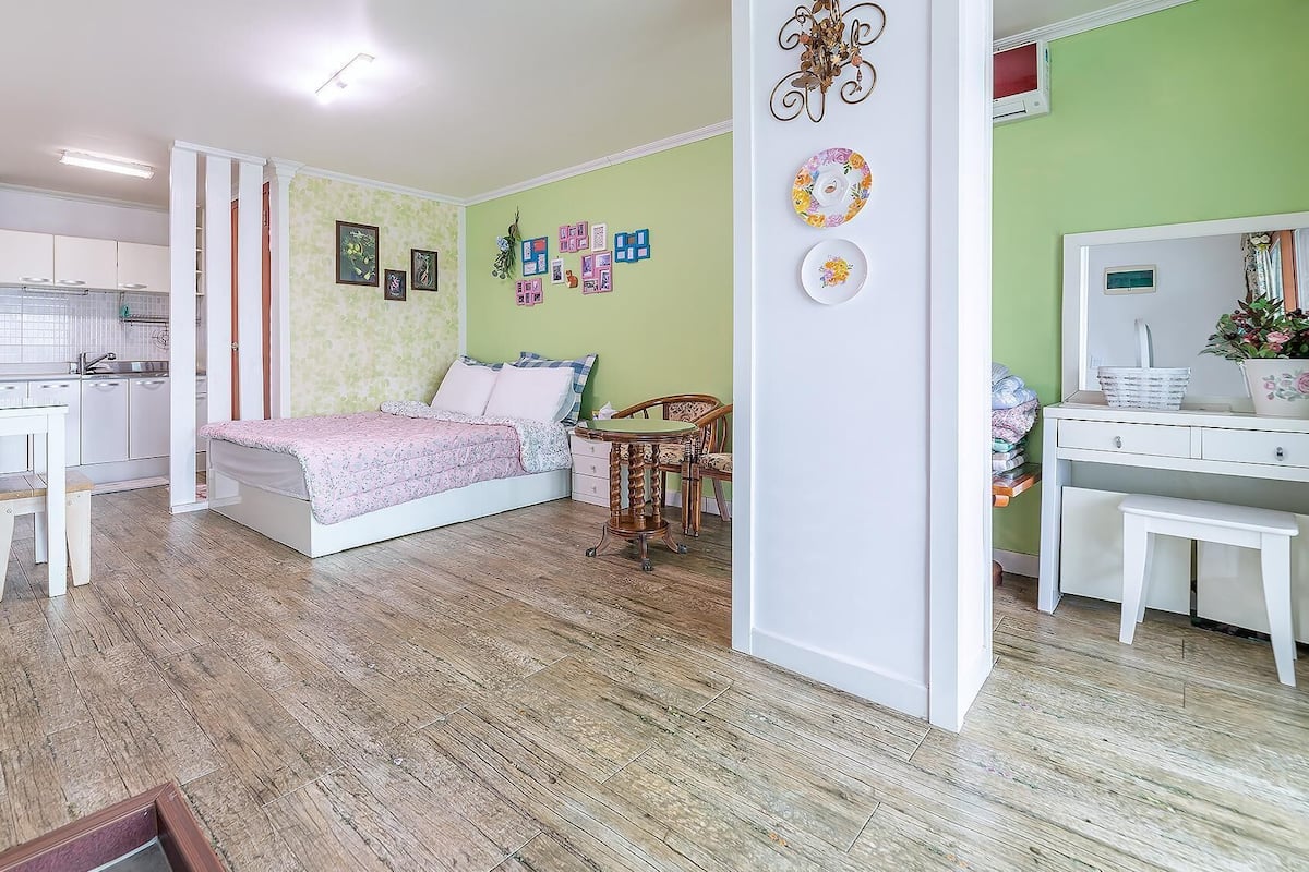 Habitació compacta amb llit, escriptori, cadira i petita cuina.