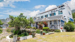 A large, white building with blue trim and a sign that reads "The Garden of Eden." - Ganghwa Edenjungwon Pension (Incheon)