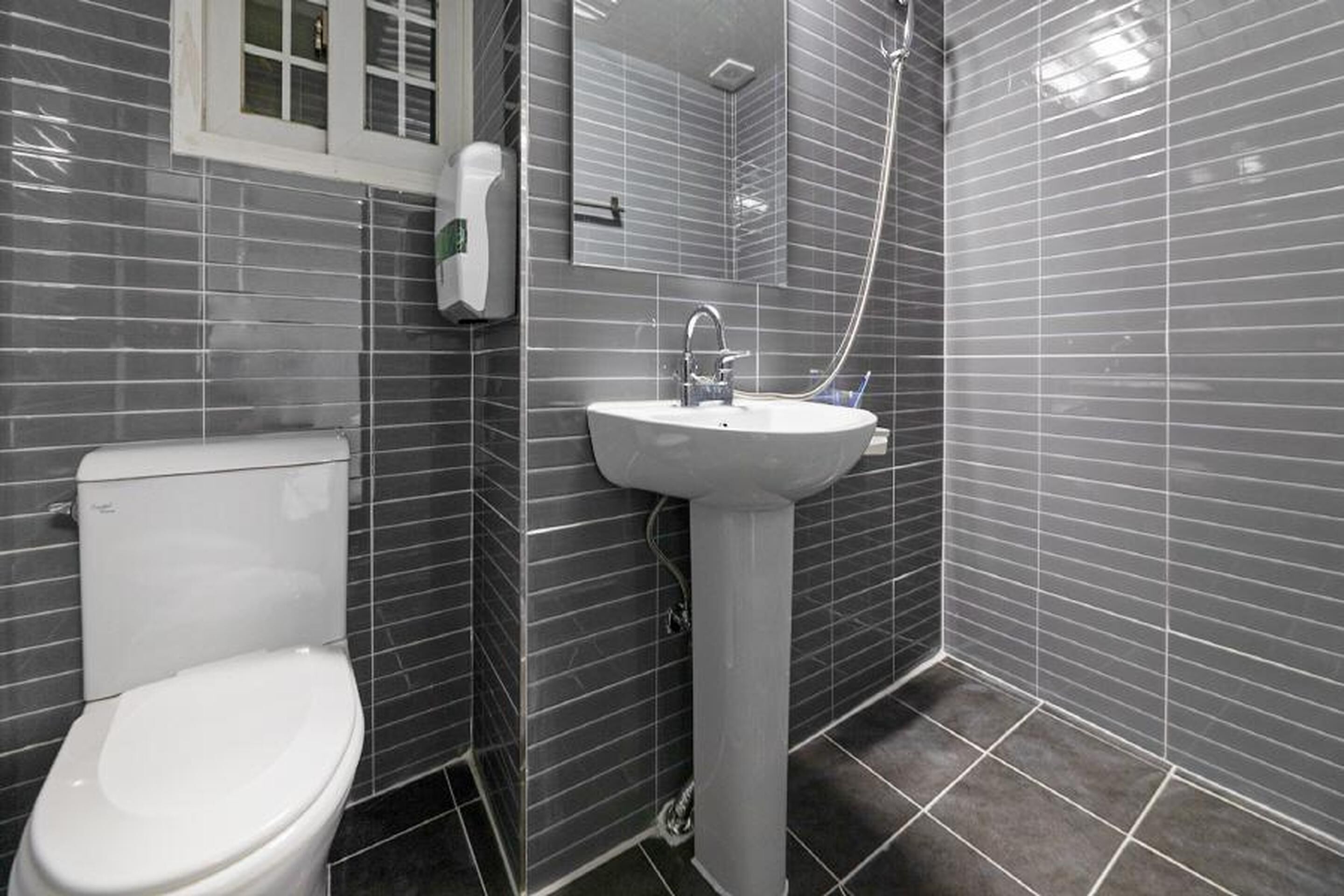 A bathroom with a white toilet, a pedestal sink, and a shower area.
