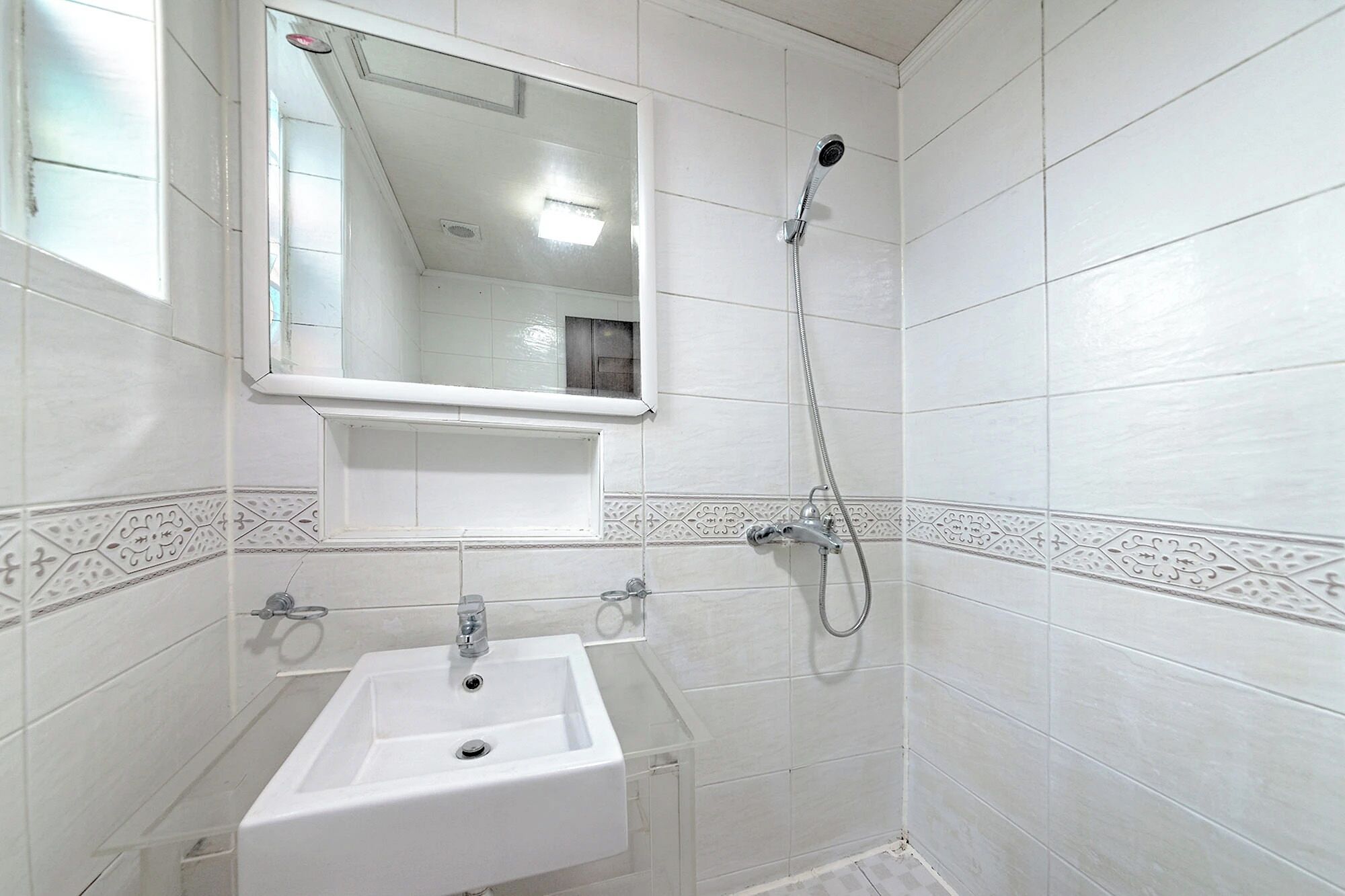 A bathroom with a white sink, a mirror, and a shower.