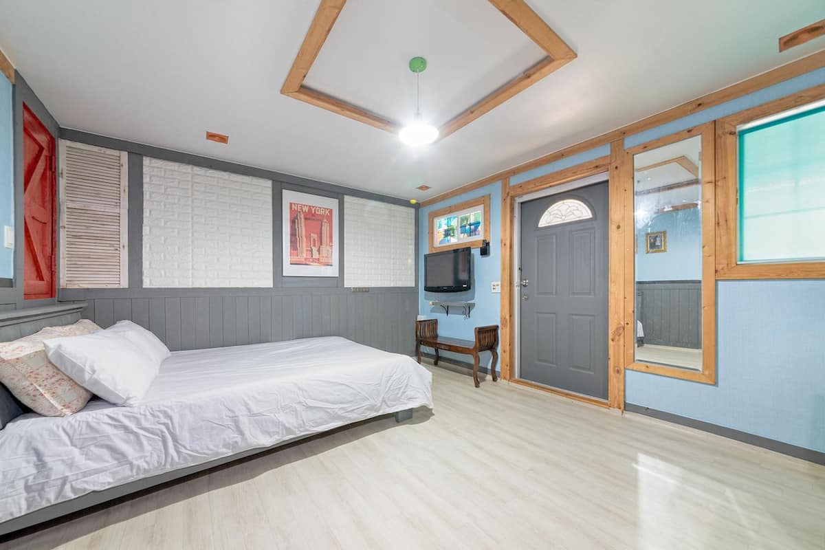 Une chambre à coucher avec un lit, une télévision, une porte et une fenêtre.
