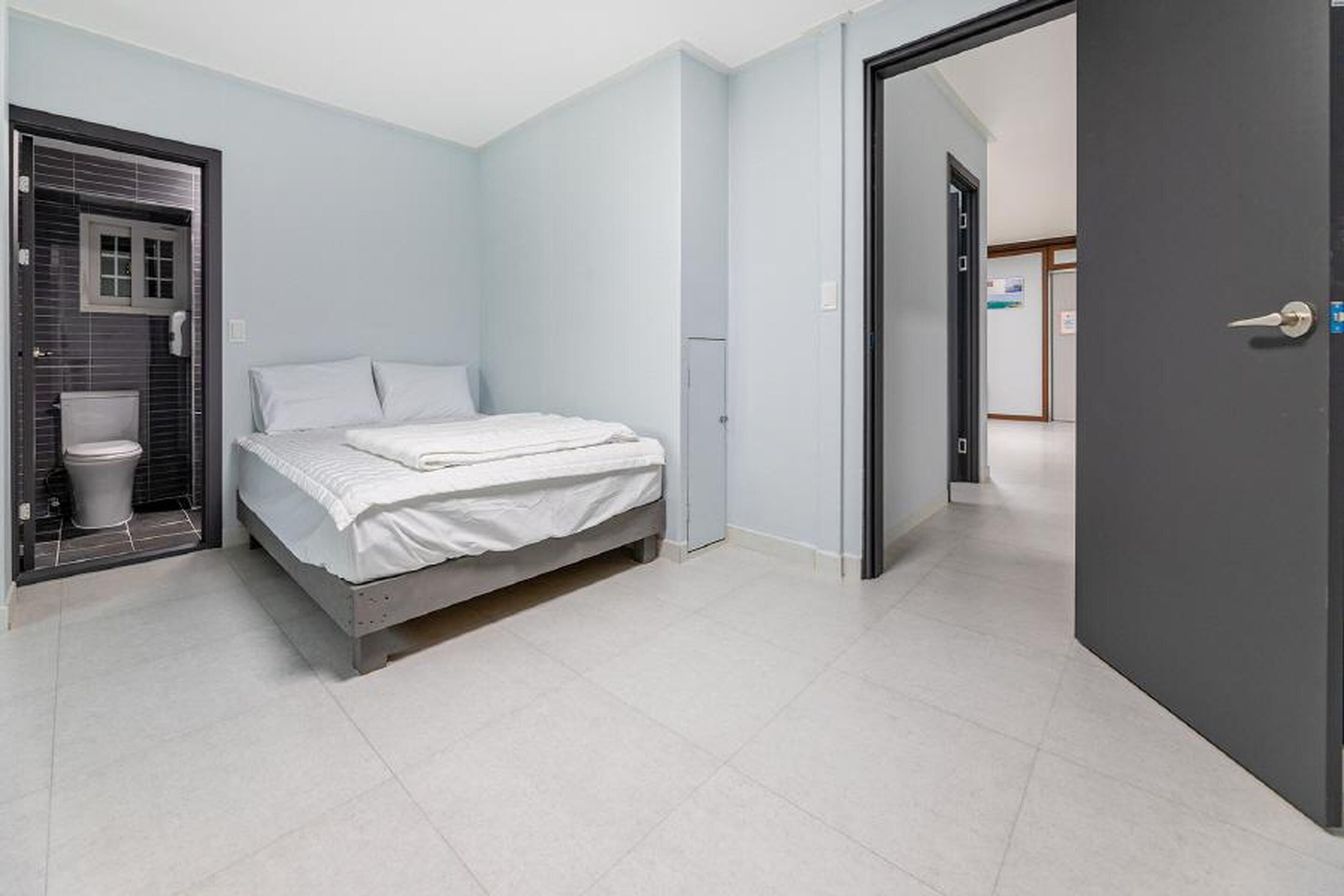 A bedroom with a bed, a toilet, and a door leading to another room.