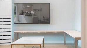 A modern interior with a flat-screen TV mounted on the wall displaying the word 'playlist.'