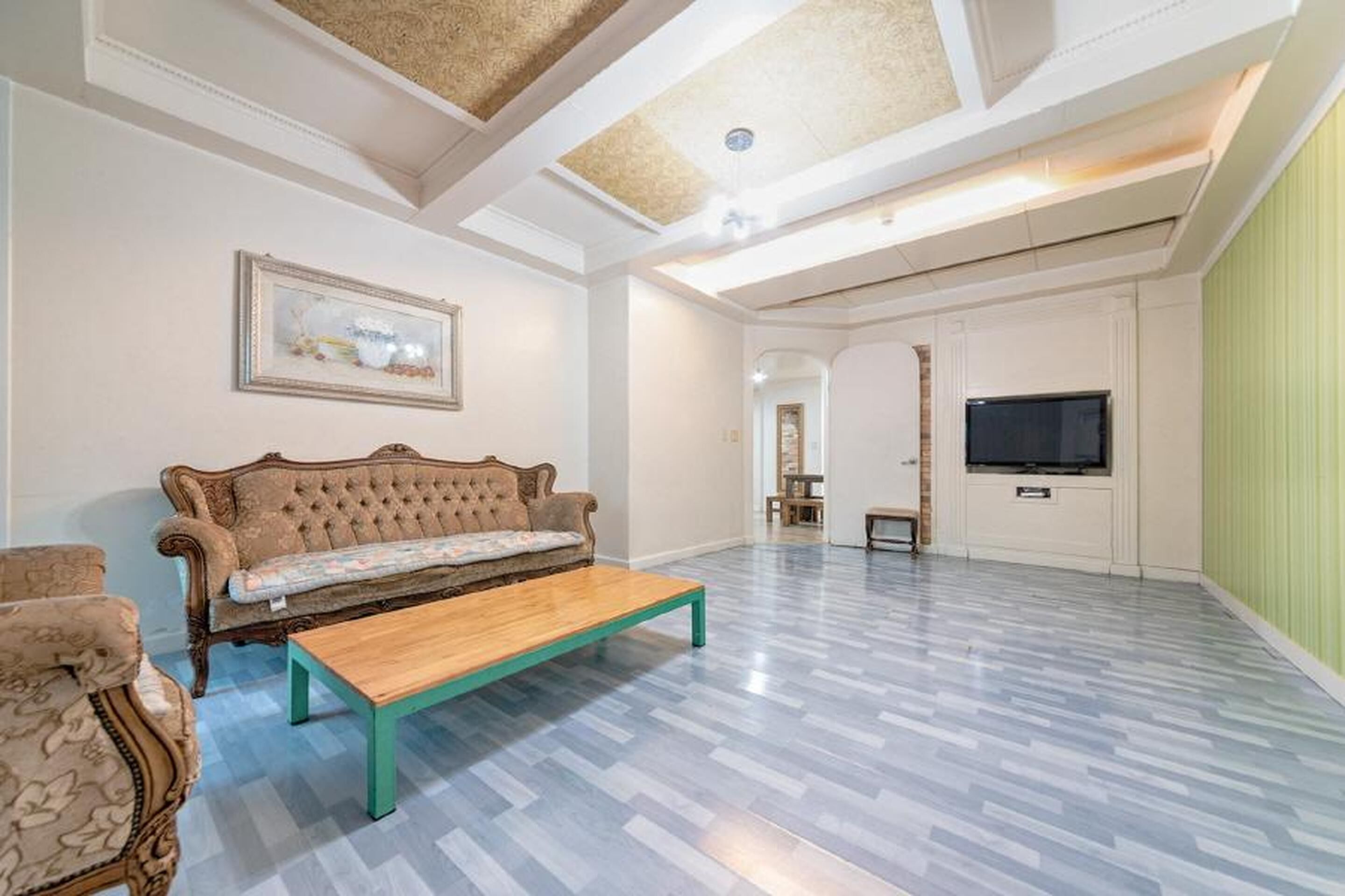 Un salon spacieux avec un sol à motifs, un canapé, une table basse et un téléviseur.