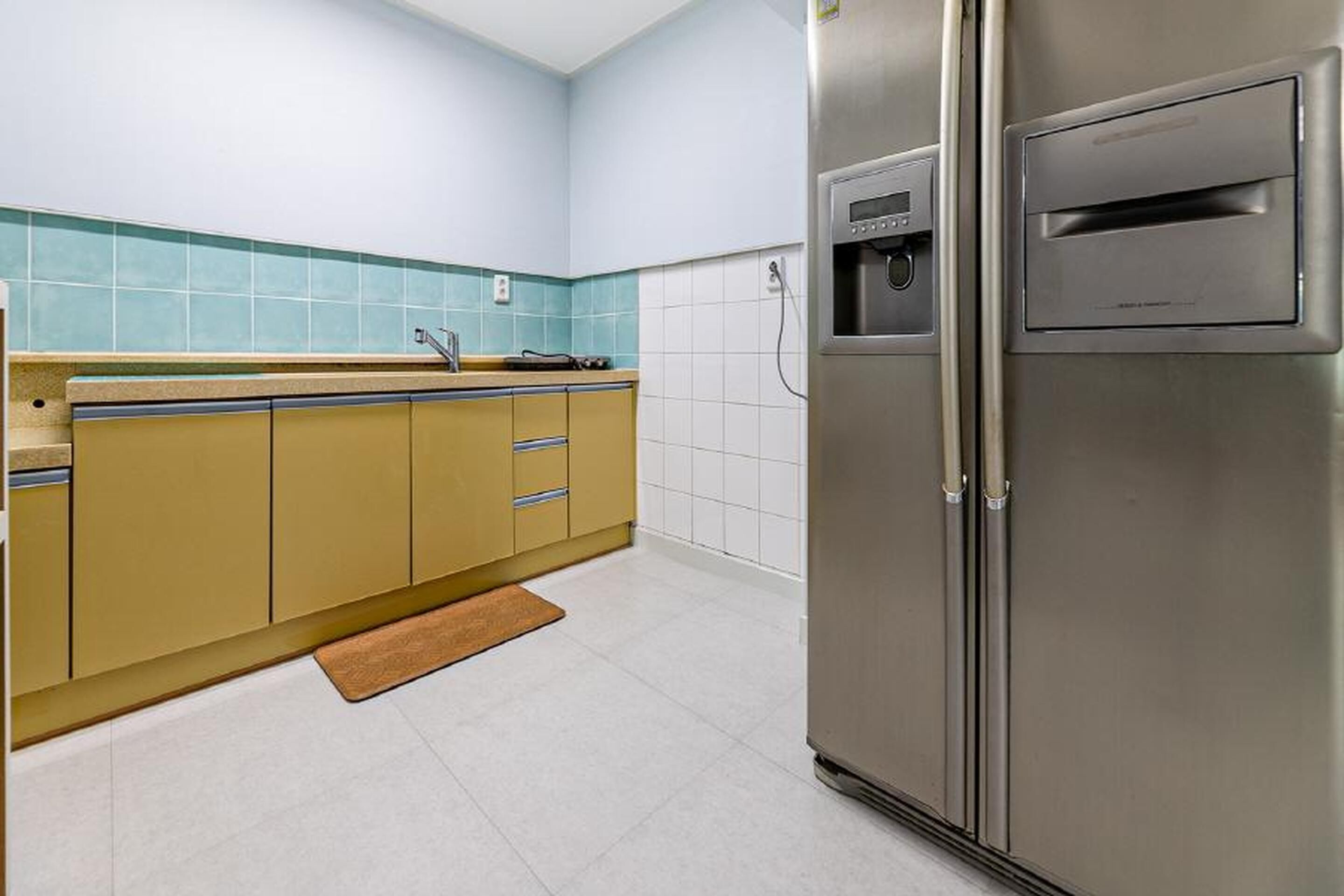 Una cocina con un refrigerador de acero inoxidable, un lavamanos y una encimera.