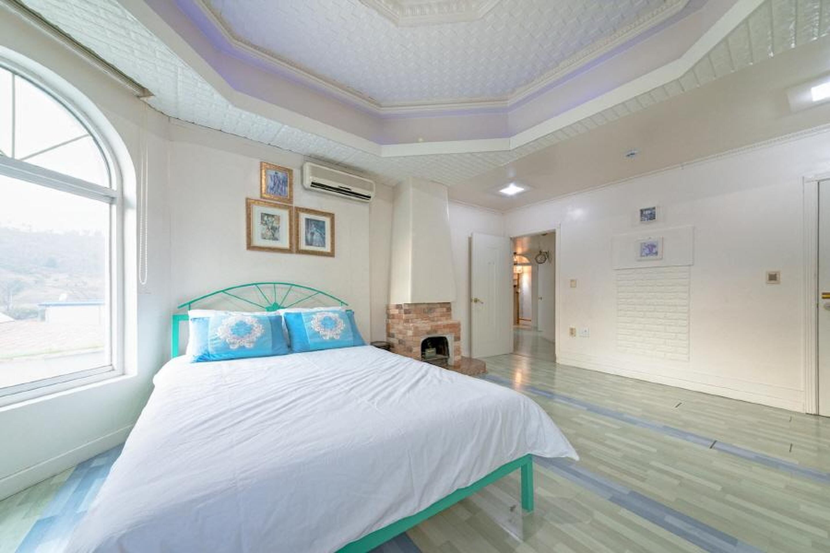 Un dormitorio con cama, chimenea y una ventana grande.