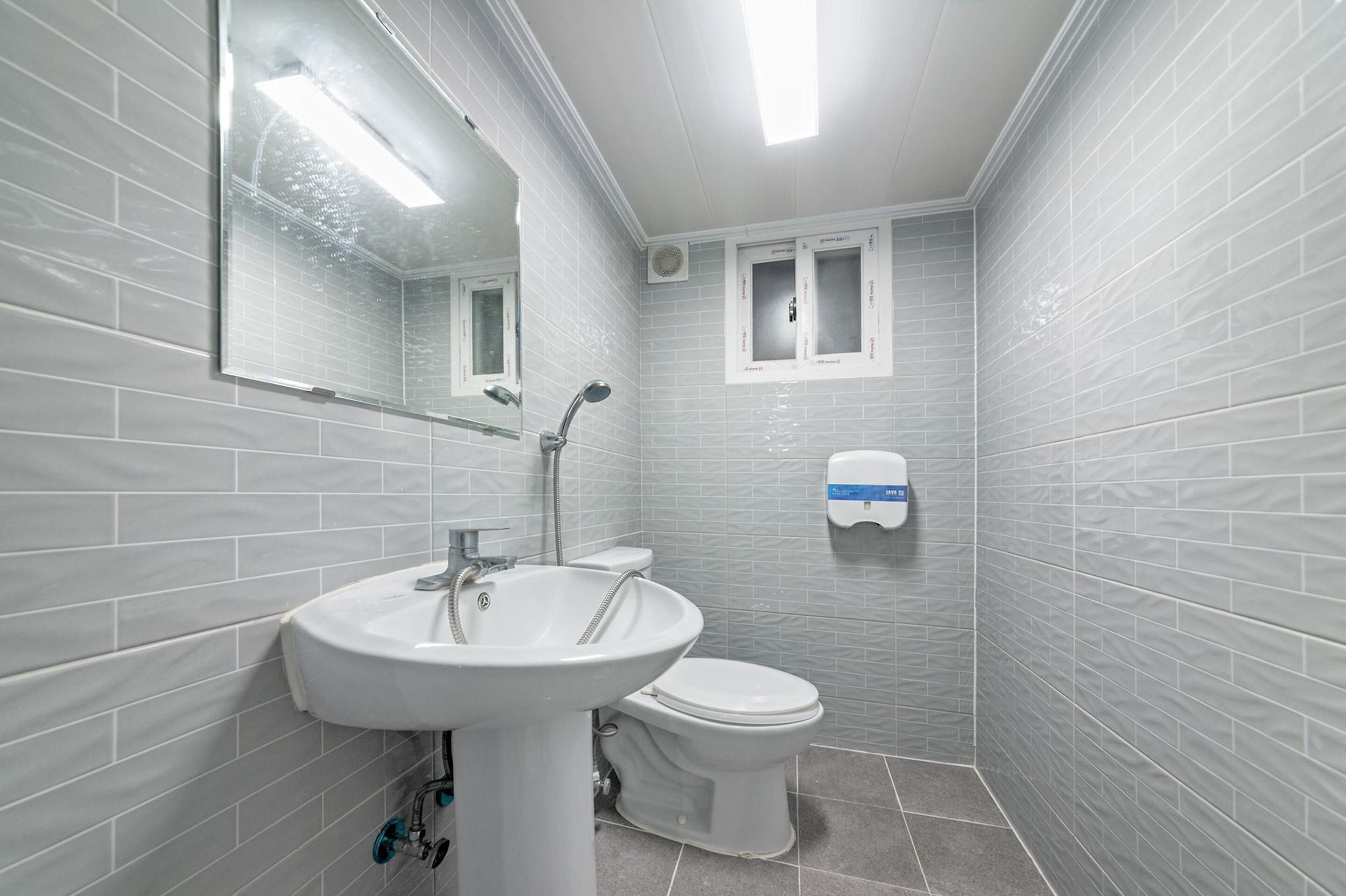 A bathroom with a white sink, toilet, and a mirror.