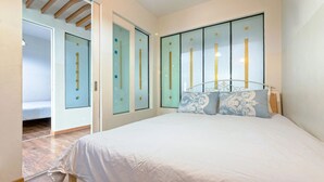Een slaapkamer met een bed, een kledingkast en een deur naar een andere kamer.
