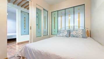 Un dormitorio con cama, armario y puerta que da a otra habitación.