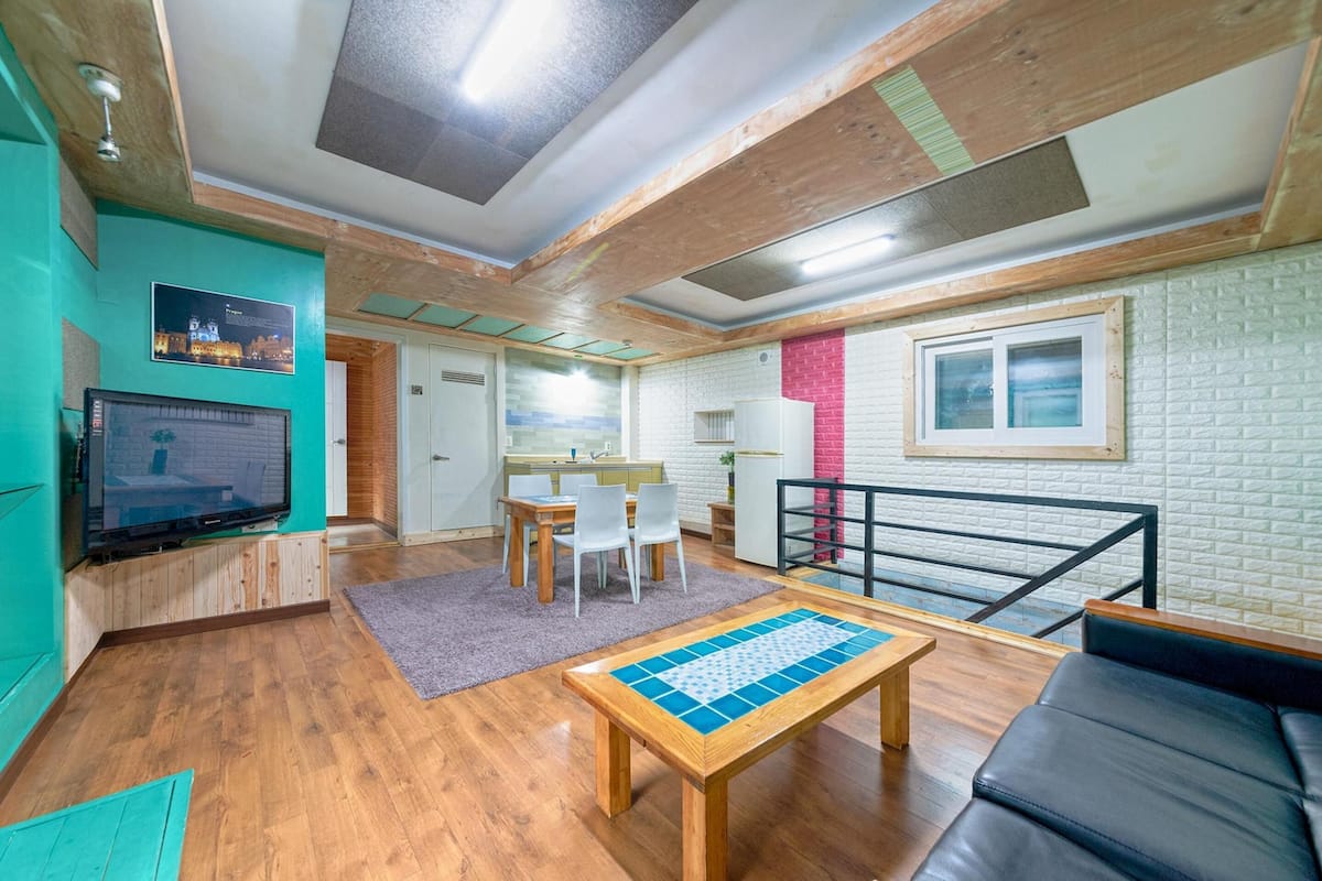 Un salon moderne avec un plafond en bois, un téléviseur, un coin repas et un balcon offrant une vue dégagée.