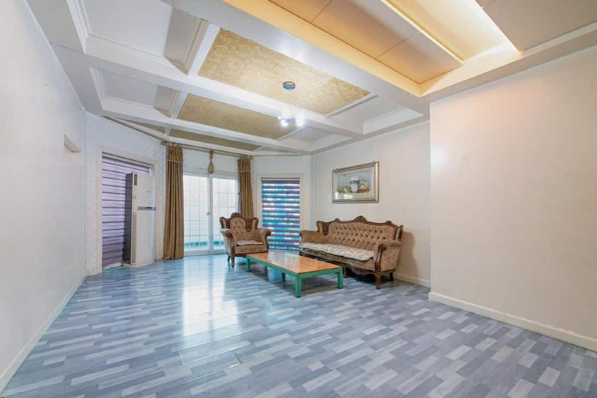 Un salon spacieux doté d’un sol à motifs, d’un canapé, de deux fauteuils et d’une table basse.