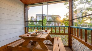 A wooden deck with a picnic table set up, overlooking a residential area with houses and trees. - Sokcho Dderak Pension (Sokcho)